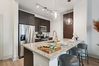 A kitchen with a granite countertop and stainless steel appliances.